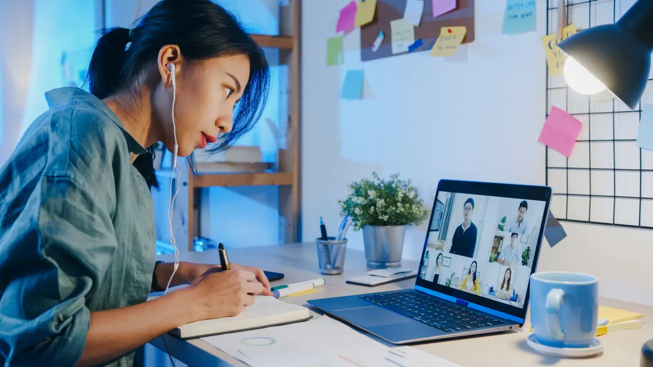 virtual meeting set up while taking notes in a near desk of a girl tech savvy