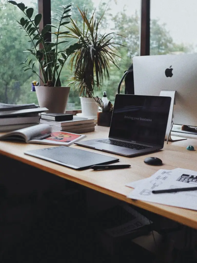 a laptop on a top of desk with a text saying "driving your business" and office set up for a rainy day morning