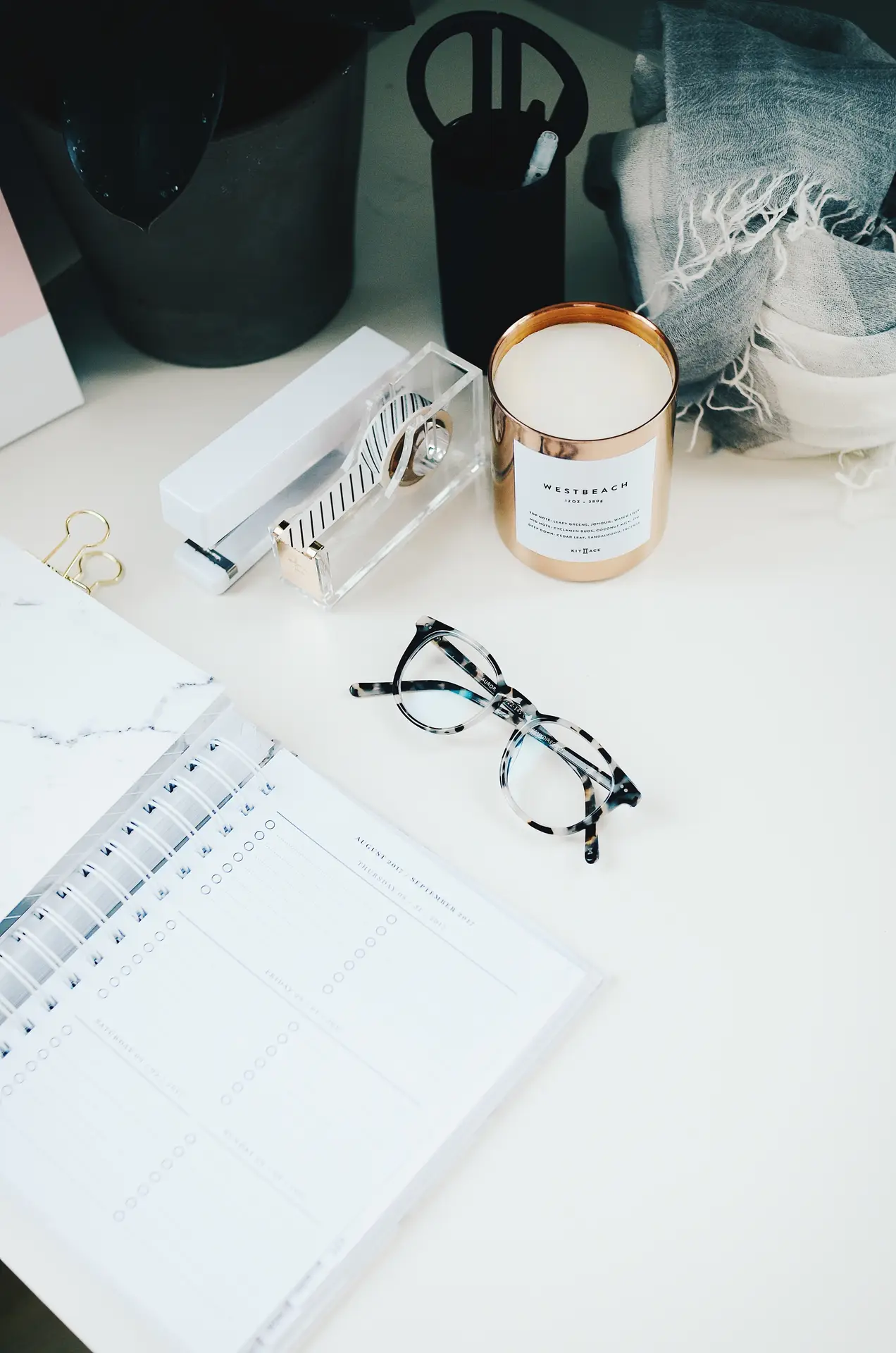 a clean desk space with notebook ready for taking notes for a meeting with reading glass and other office supplies in clean