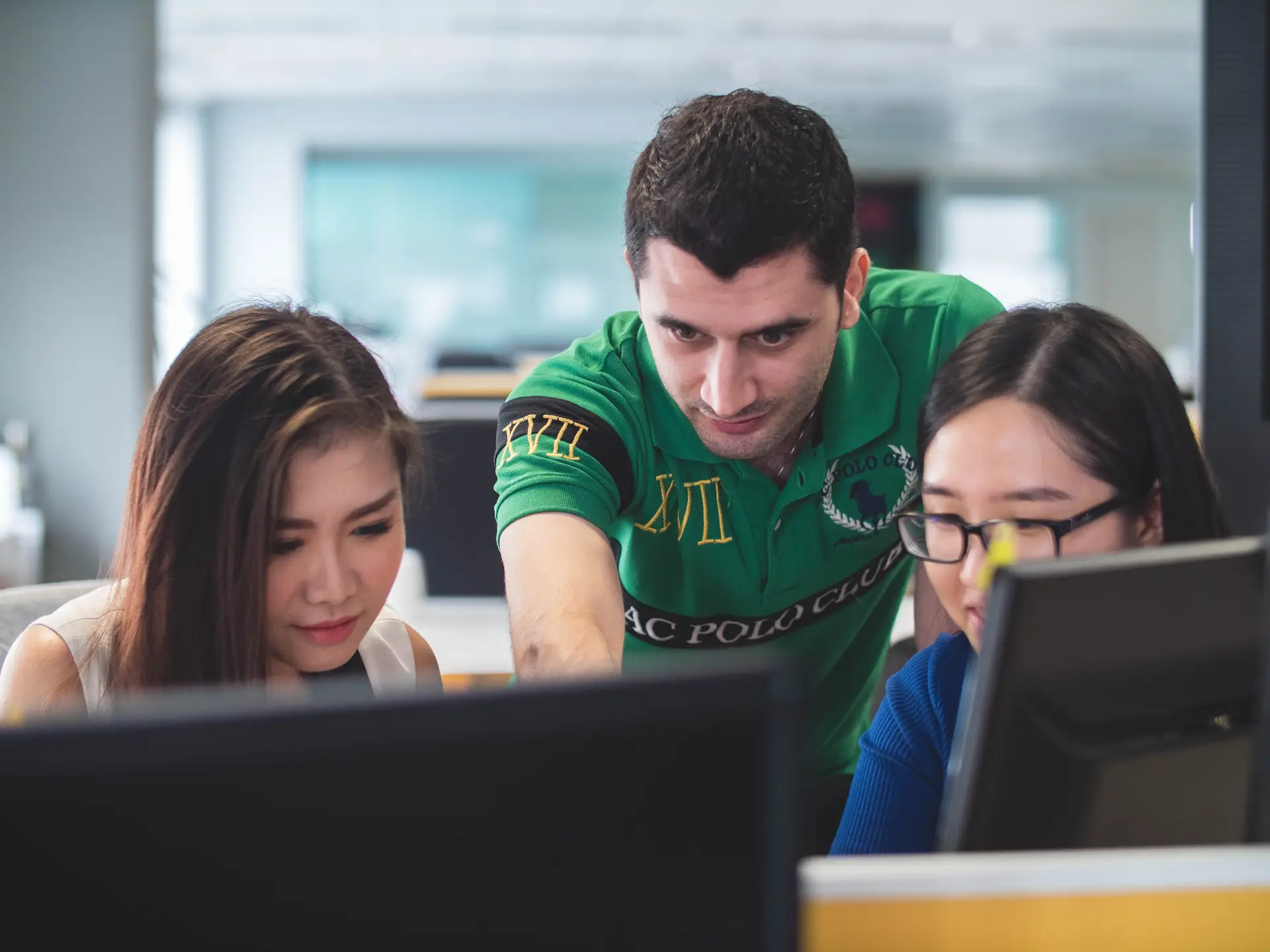 a group of 3 professional looking at one monitor and one professional at the middle pointing something on the screen for presentations