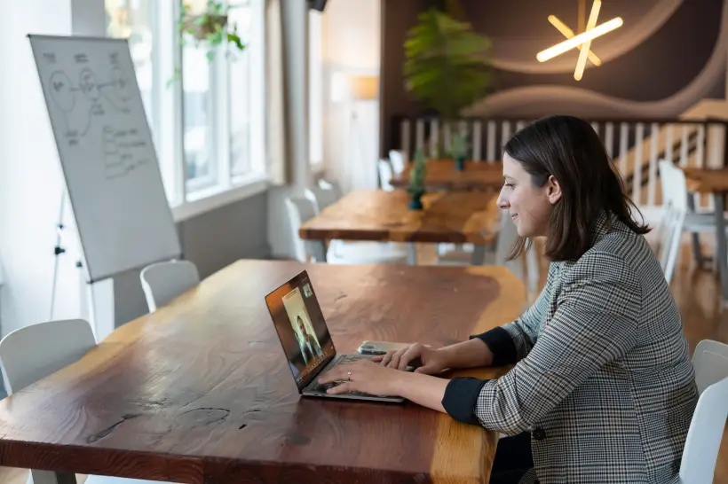 a discovery call or virtual meeting of a professional women facing her laptop with her client or boss while sitting in a cozy coffee shop