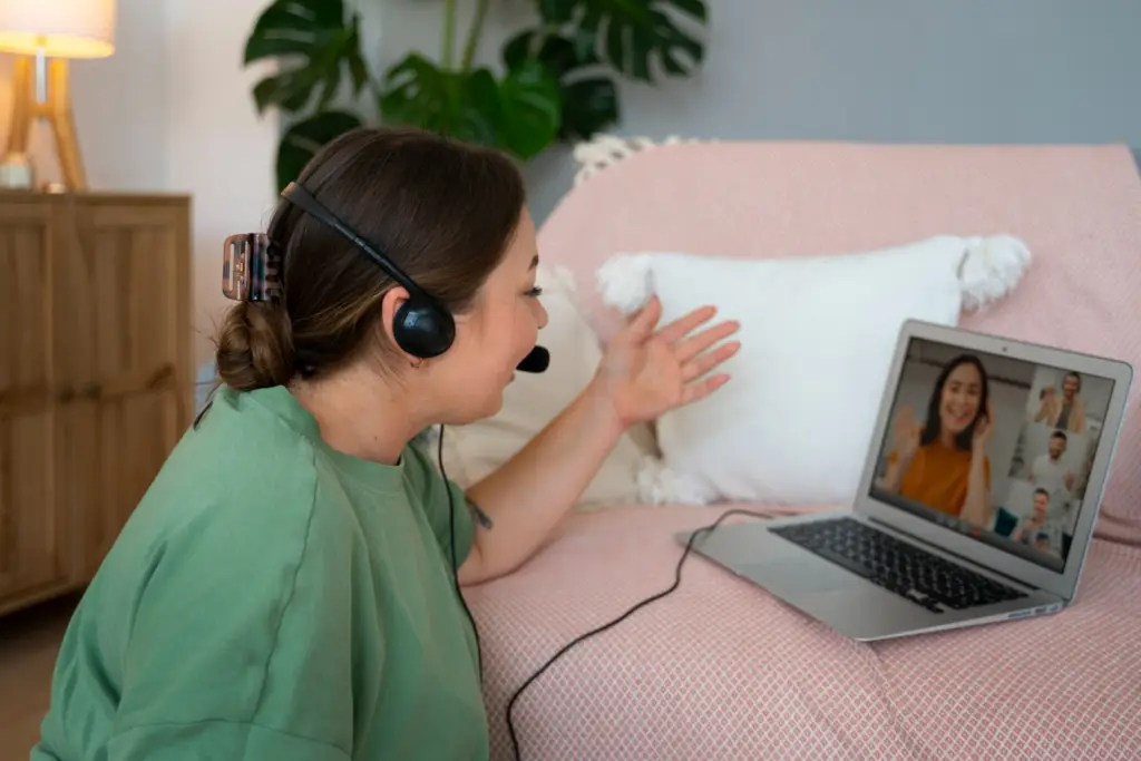 a call center mom facing his virtual peers during a virtual meeting while her headset is on in a living room set up